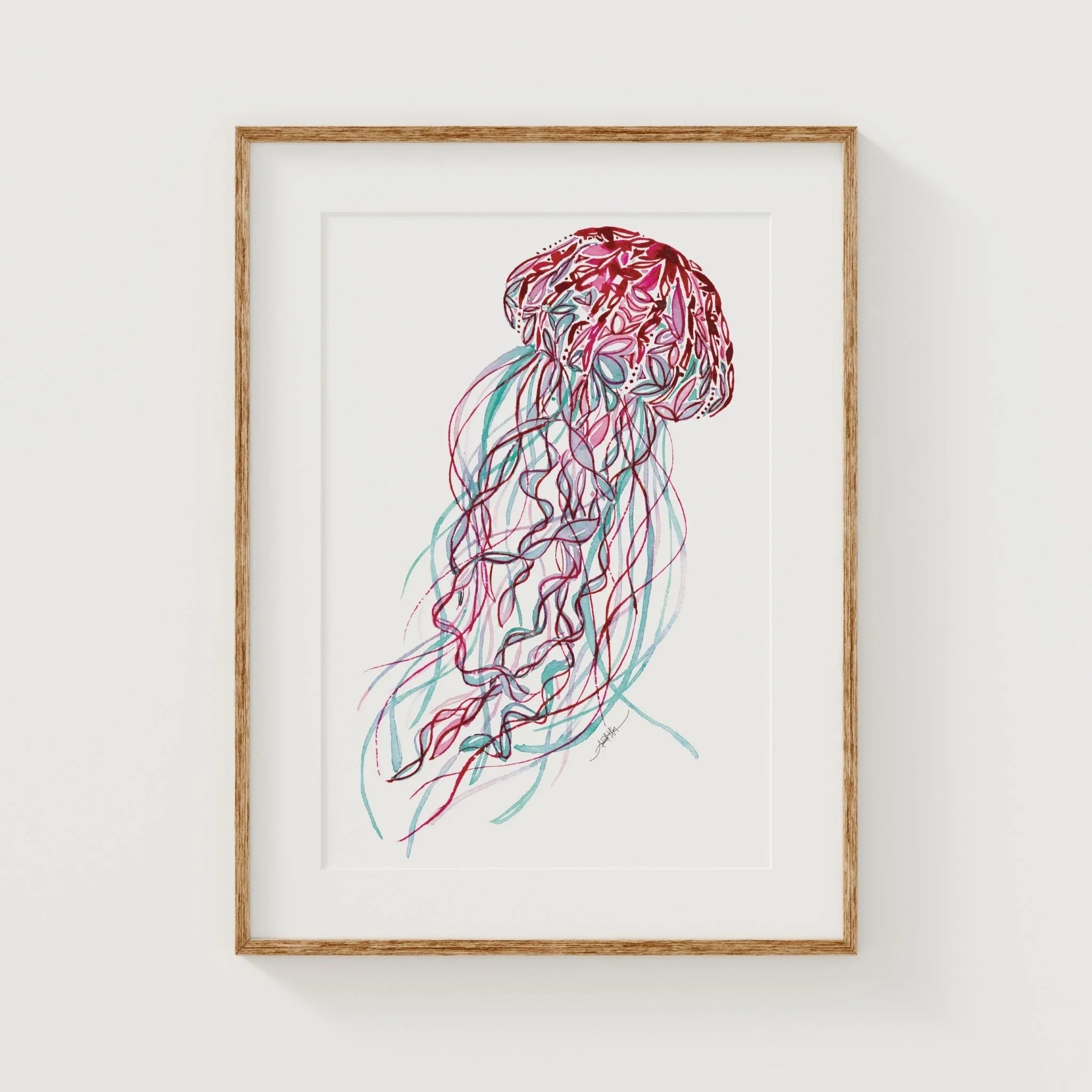 Framed jellyfish wall art print with pink and teal watercolor design, perfect for coastal home decor