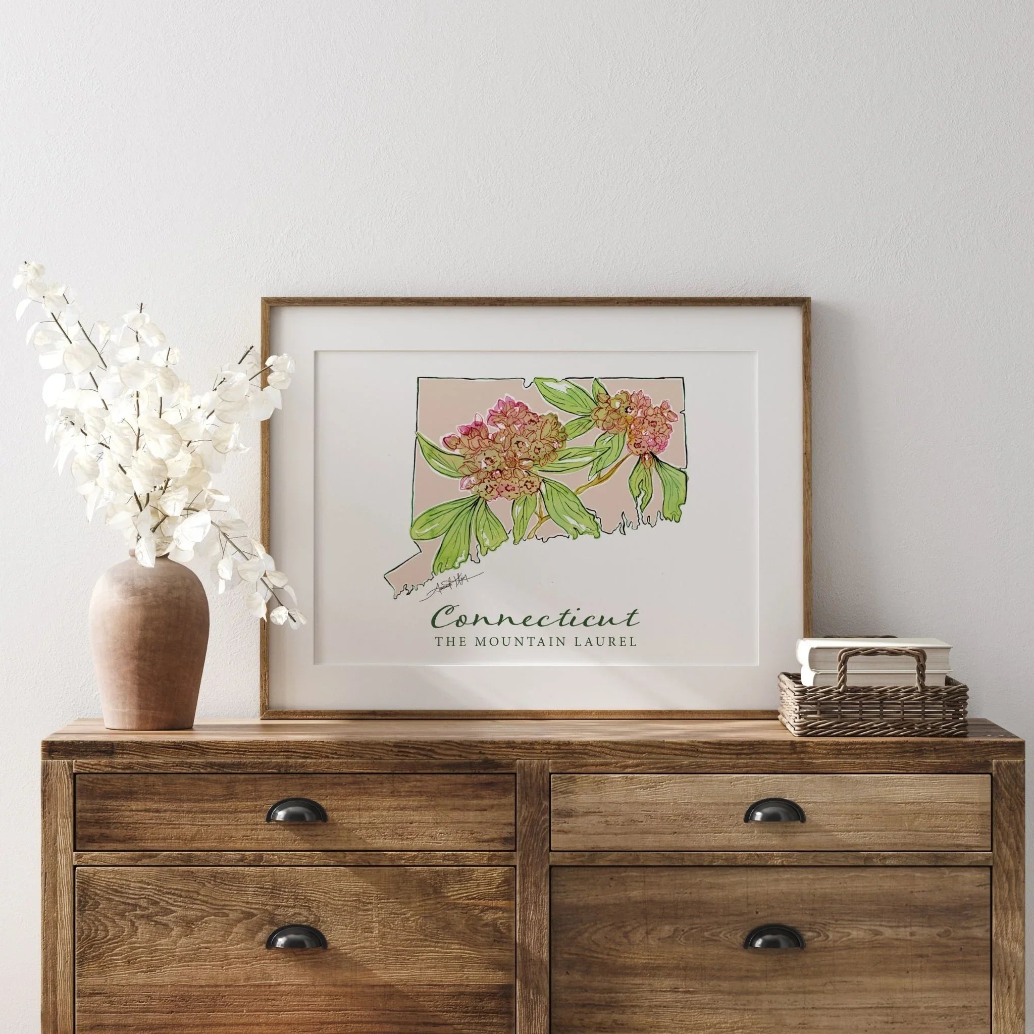 Framed Connecticut state art print with mountain laurel flowers, displayed on wooden console table