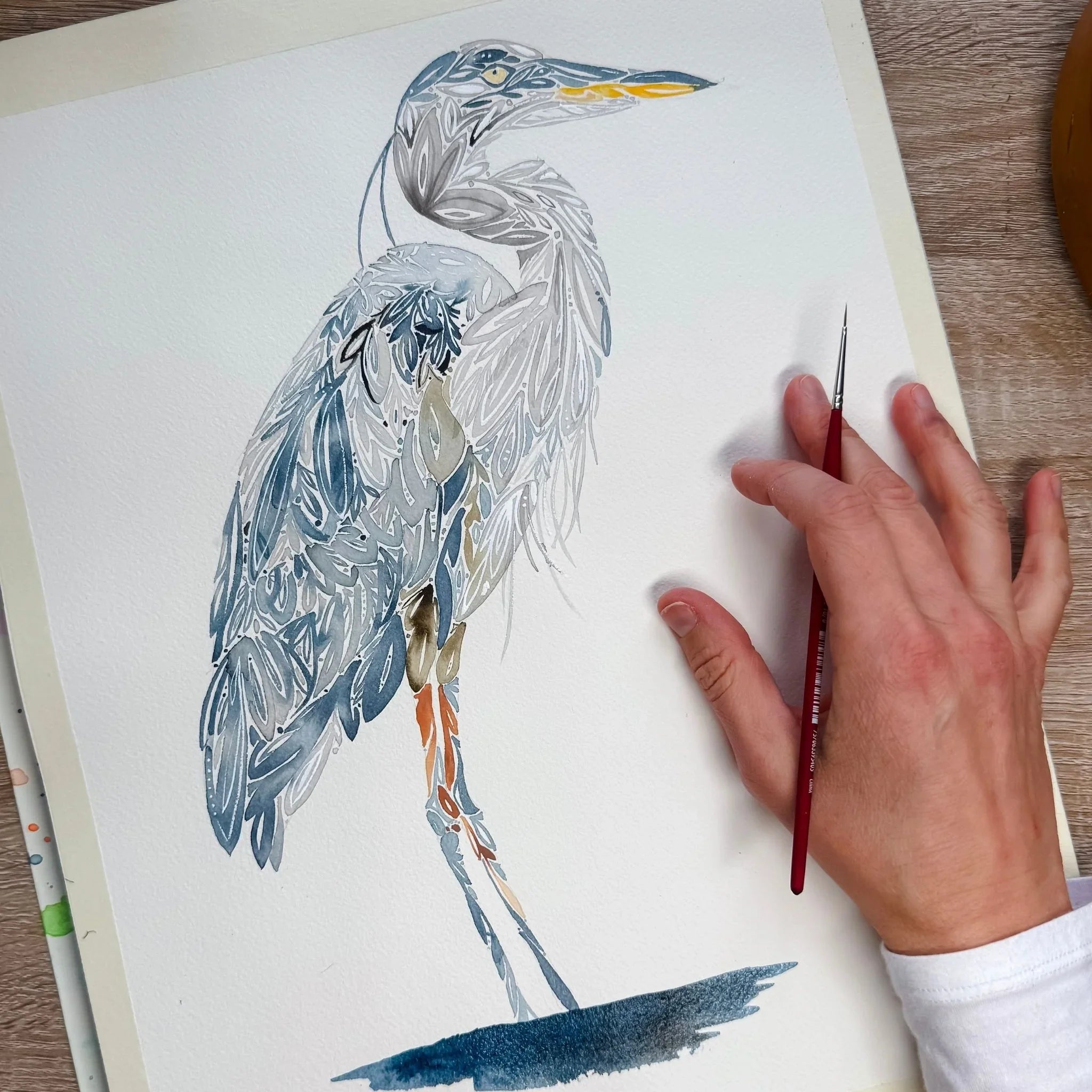 Hand-painted heron watercolor artwork with intricate feather details and artist's brush