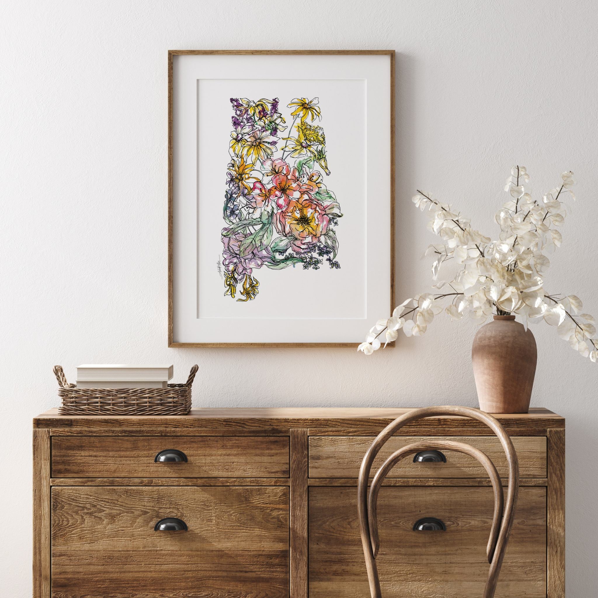 Floral Alabama artwork on a wall above a wooden sideboard with a vase and chair.